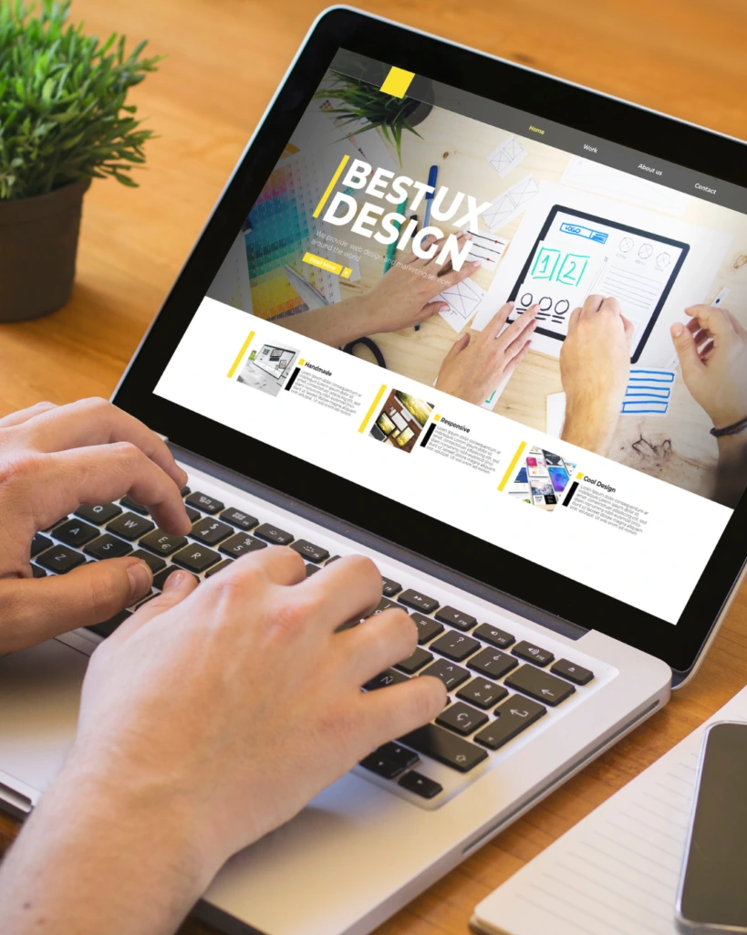 Hands typing on a laptop showing a web design portfolio