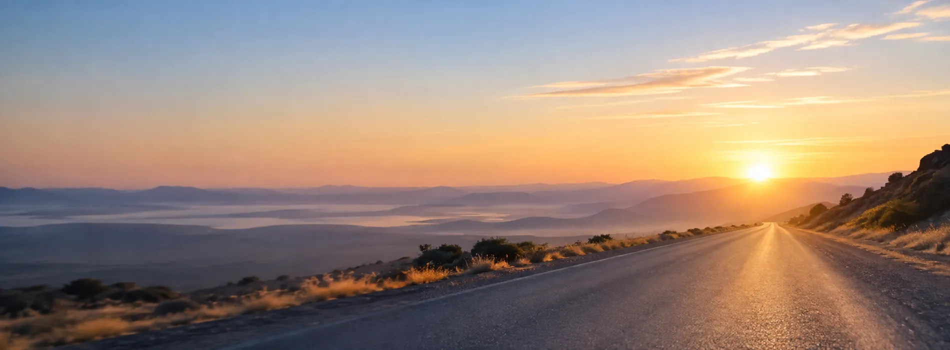 An open road stretching toward mountains at sunrise