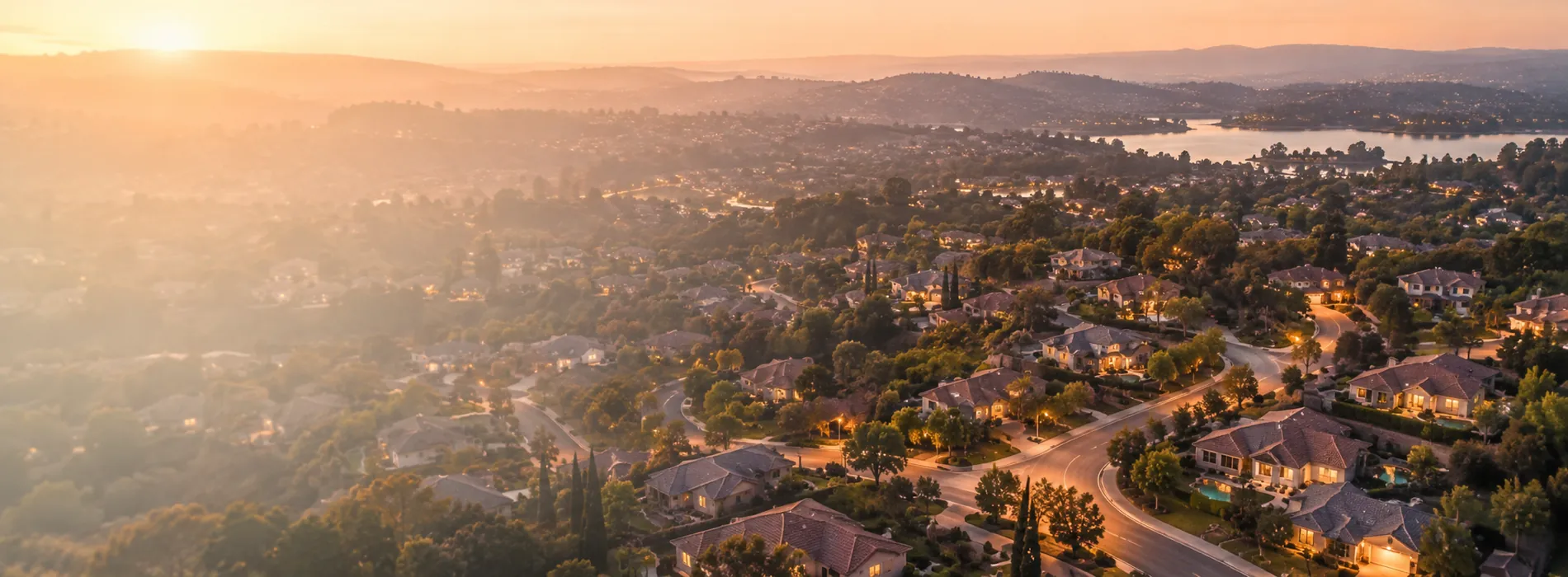 An aerial view of a suburban neighborhood at dusk as streetlights come on