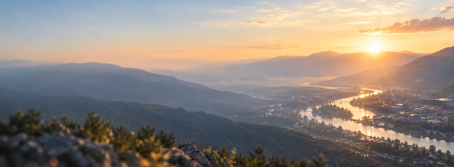 A wide mountain valley at first light with a river catching the sun