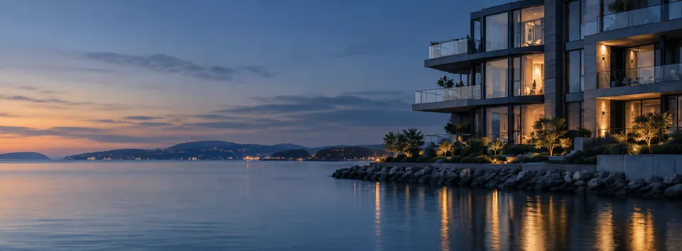 A modern waterfront apartment building at blue hour with warm lit windows