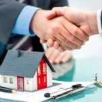 residential-property-management - Kihan Marketing Handshake between two professionals over a miniature house model on a desk with documents, a pen, and keys nearby.