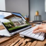 THRESHOLD1573_SocialPosts_June_Blog_2560x1707_V1_PropertyManagementSoftware-new - Kihan Marketing Person typing at a desk with a tablet showing a modern house image on screen