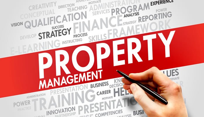 Hand holding a pen across a red PROPERTY MANAGEMENT banner, with a gray word cloud about finance, training, and strategy in the background.