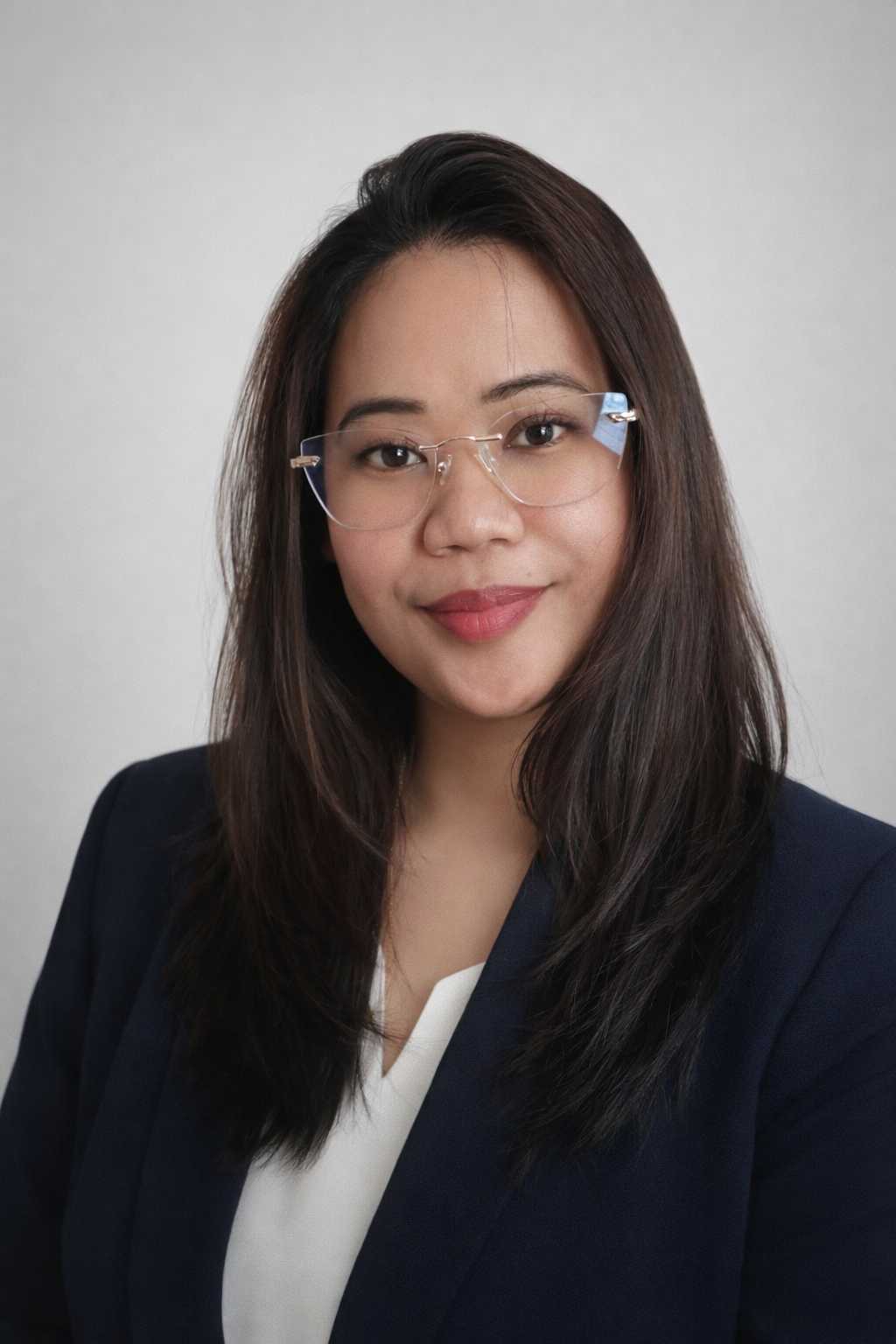 Professional headshot of a woman with long dark hair and glasses, wearing a navy blazer and white blouse, smiling at the camera.