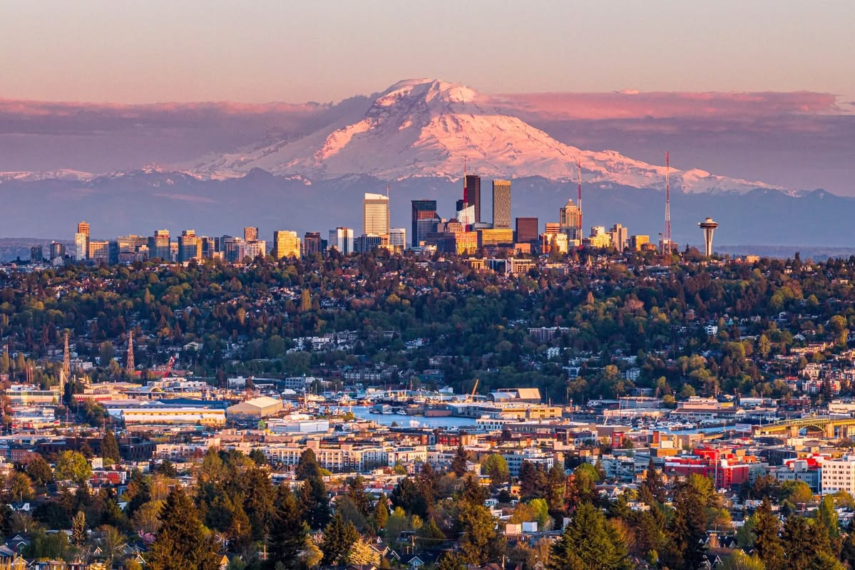 Seattle skyline with Mount Rainier in the snowy backdrop at sunset.