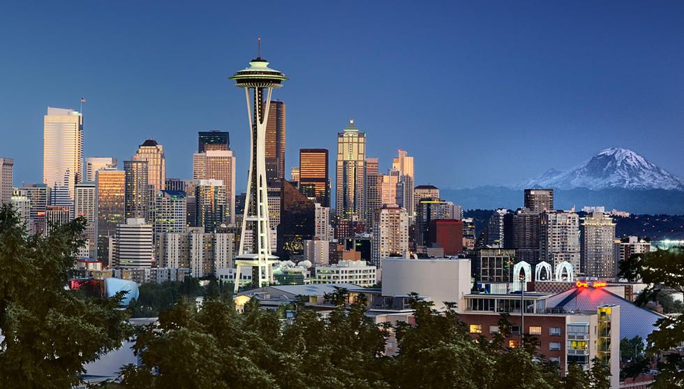 Seattle skyline at dusk with Space Needle and Mount Rainier in the distance.
