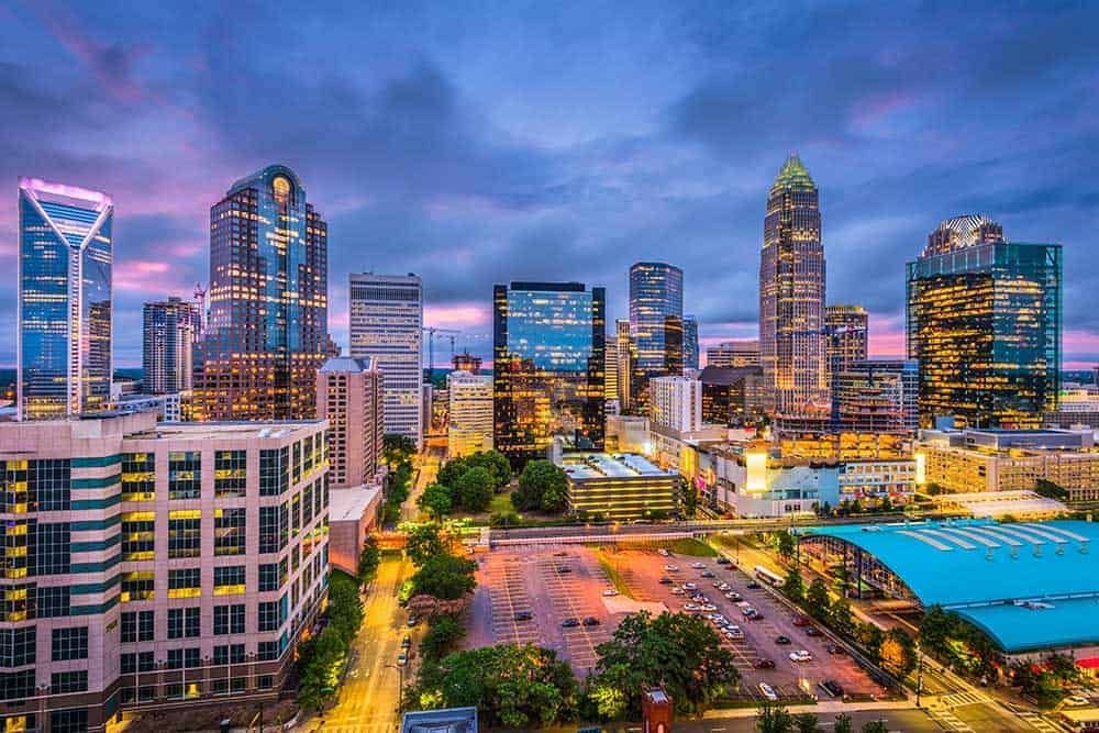 Evening city skyline with modern glass skyscrapers and illuminated streets viewed from above.