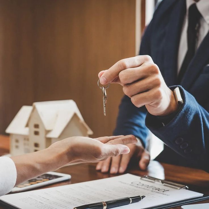 6143386d486060db0e74ec27e3d4d36d - Kihan Marketing - Kihan Marketing Businessperson in a suit hands over keys to a client over a desk with a contract and a small model house in the background, indicating a real estate transaction.