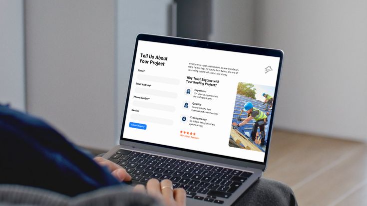 Person using a laptop displaying a 'Tell Us About Your Project' inquiry form alongside a construction photo on the screen.