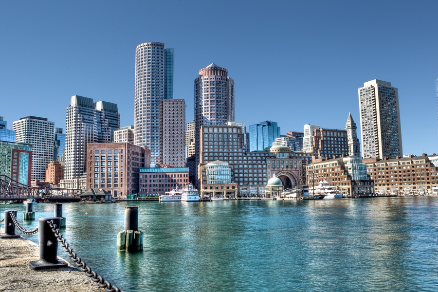 City skyline along the waterfront with tall buildings and calm harbor in the foreground.
