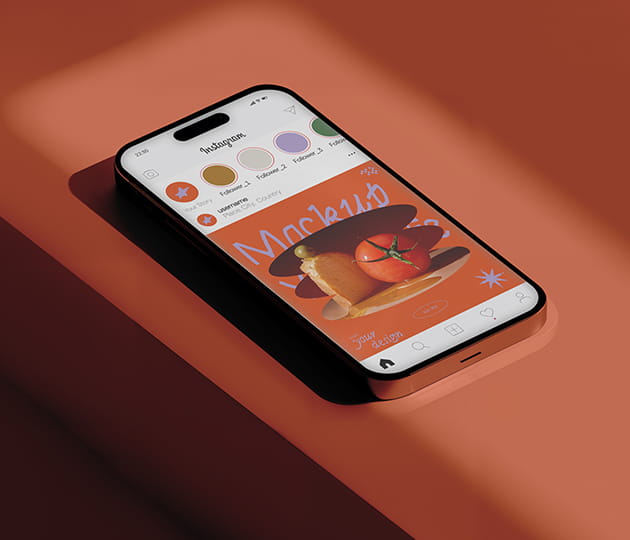 Smartphone lying on an orange surface showing an Instagram feed with an orange-themed post and story circles