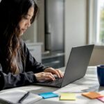 Hands typing on laptop setting up ads